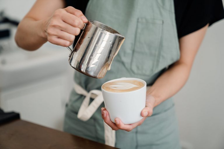 anonymous person preparing coffee to client in cafe