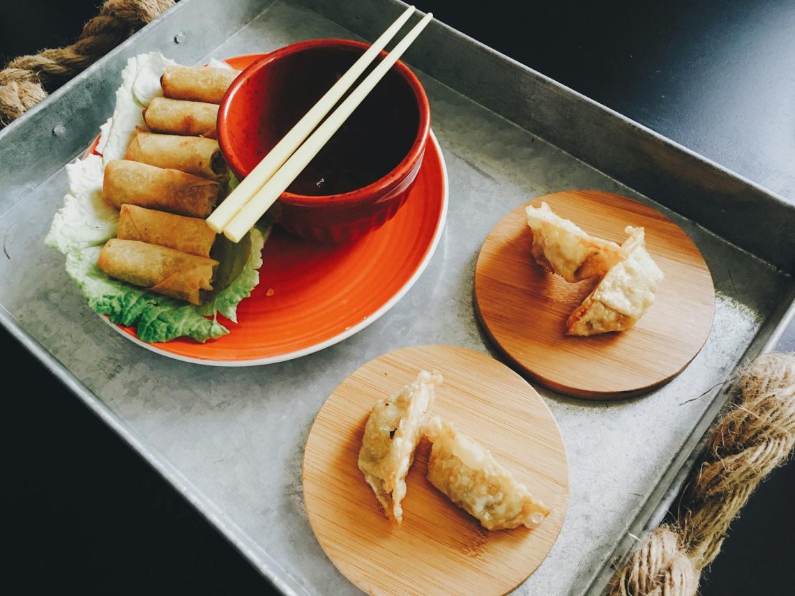 fried spring rolls and dumplings on top of tray