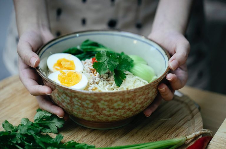 crop unrecognizable woman touching bowl with traditional ramen soup