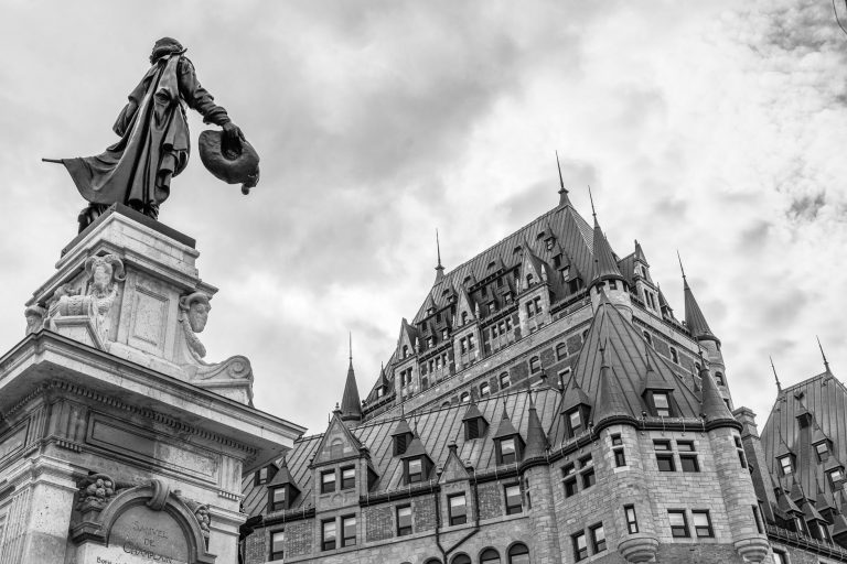 grayscale photo of statue of man on top of building